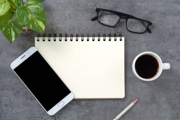 istock Mobile phone with blank mockup screen and book on stone texture background.Work desk. Top view. Flat lay. 1720215189