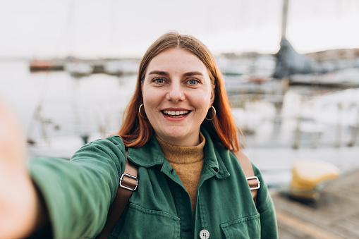 Happy Women taking selfie. Young beautiful girl say Hi Tourist walking along the waterfront, seaside. Vacation concept by exploring interesting places to travel