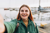 Happy 30s Women taking selfie. Young beautiful girl say Hi Tourist walking along the waterfront, seaside. Vacation concept by exploring interesting places to travel
