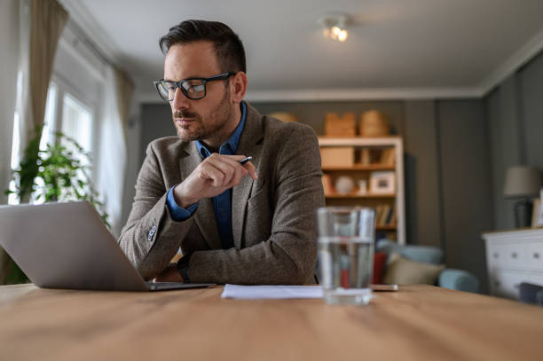 istock Low angle view of elegant male entrepreneur reading e-mail over computer while working from home 1720238774