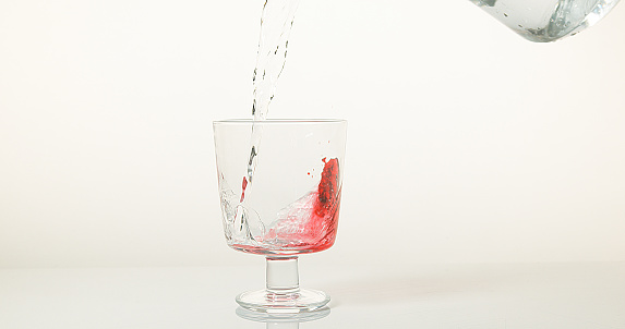 Bottle of water pouring into a glass cup.