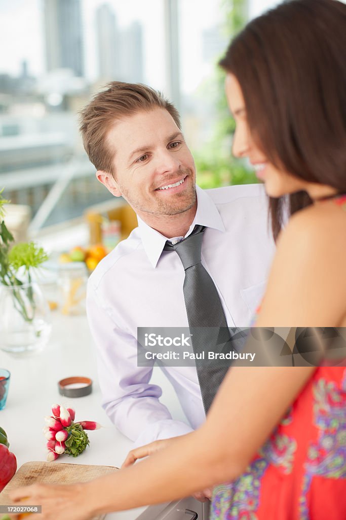 Marido hablando de mujer mientras la paciente parte de las verduras en la cocina - Foto de stock de 25-29 años libre de derechos