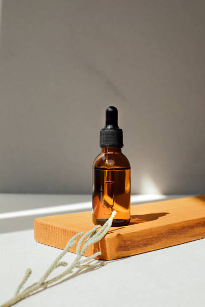 Amber bottle with facial cosmetics, liquid on a wooden tray on the light concrete background stock photo