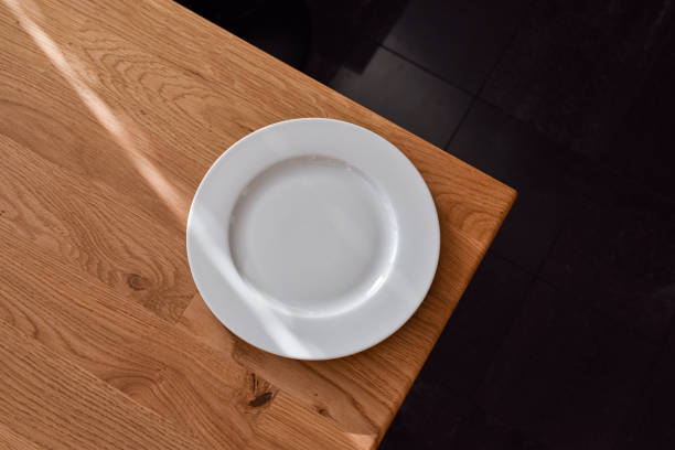 istock Ceramic white flat plate for food on wooden table top view 1720309469