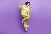 Full size photo of carefree overjoyed happy woman dance motion wear lime yellow flared outfit jumper isolated over purple color background