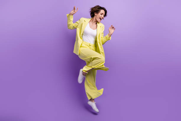 Full size photo of carefree overjoyed happy woman dance motion wear lime yellow flared outfit jumper isolated over purple color background stock photo