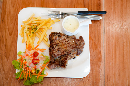 Image of black pepper pork steak and french fries on a plate at a dining table
