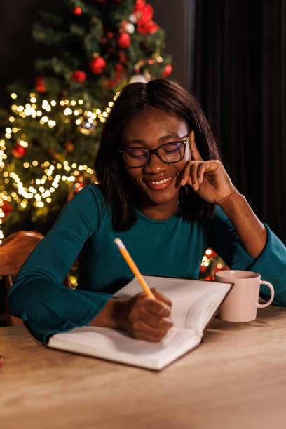 istock Young woman contemplating her New Year's resolutions and writing them in a diary 1720320442