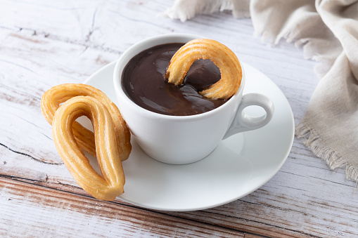 Traditional Spanish churros with hot chocolate breakfast on wooden table