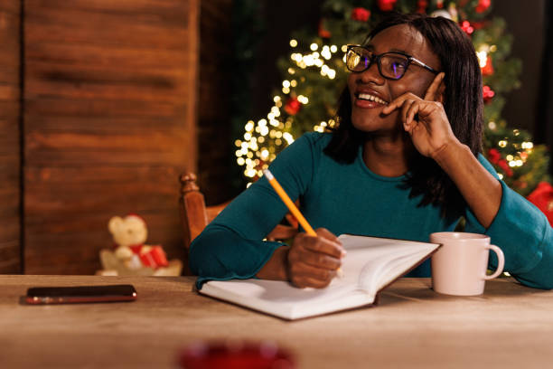 istock Young woman contemplating her New Year's resolutions and writing them in a diary 1720331509