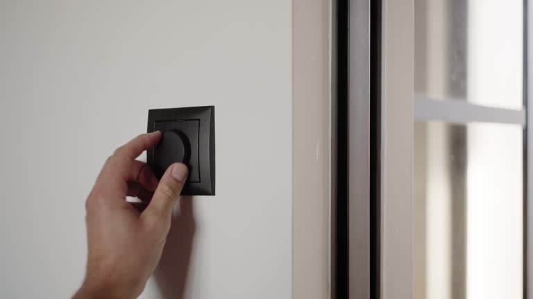 Hand using a black dimmer switch at home