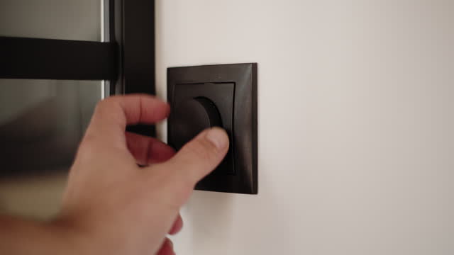 Hand turning a dimmer switch at home