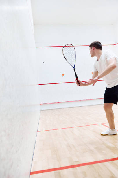 istock Young sportive man playing, training squash on squash court. Hitting ball with special racket. Concentration 1720334833