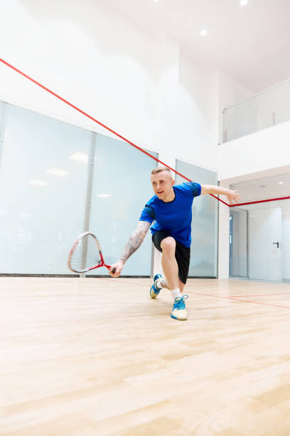 istock Young man playing, training squash on squash court. Hitting ball with special racket. Concentration 1720334850