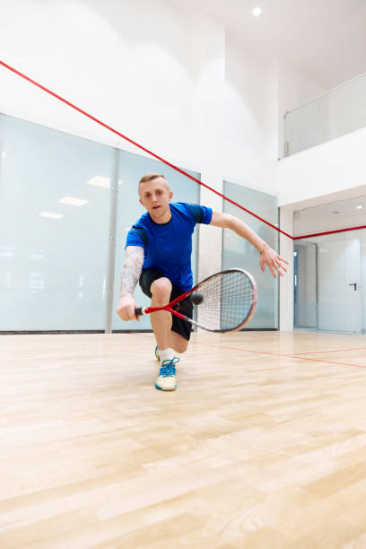 istock Young sportive man playing, training squash on squash court. Hitting ball with special racket. Concentration 1720334859