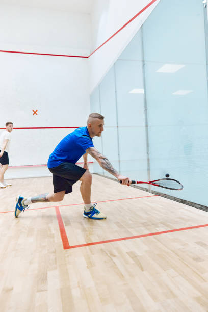 istock Activity. Young sportive guy in sportswear training, playing squash on squash court. Exercising 1720335394