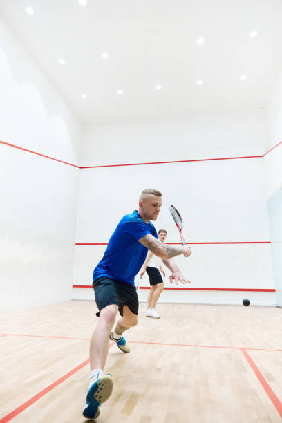 istock Activity. Young sportive guy in sportswear training, playing squash on squash court. Exercising 1720335409