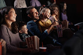 Cheerful family watching a funny movie in theatre.