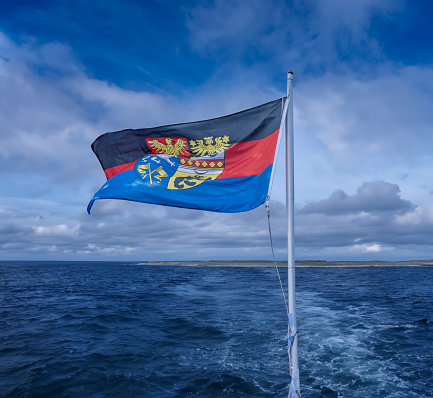 The east Frisian flag on a boat in front of an east Frisian island in Germany.