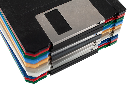 Colored old retro floppy diskettes in stack. Isolated on white background.