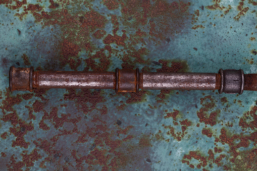 Rusty plumb tube on rusty metal wall background