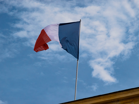 Flag of France waiving on the wind against blue sky