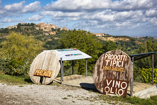 View of Montepulciano with signs in the foreground advertising local Tuscan produce.
