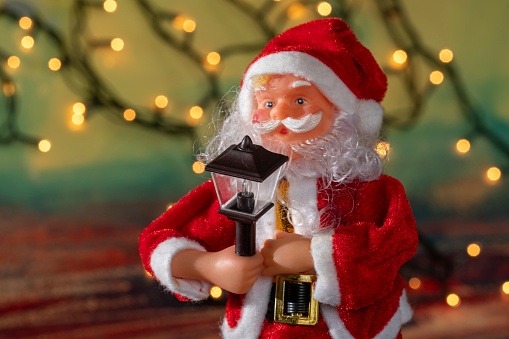 Santa claus doll with blurred christmas lights background