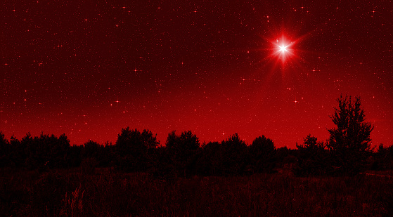 Bright star shines over the manger of christmas of Jesus Christ on red starry sky