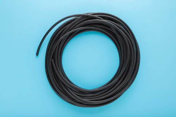 istock Black dark rolled cable on light blue table background. Pastel color. Closeup. Top down view. 1720442938