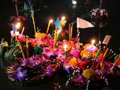 Krathongs floating on the water. Loy Krathong Festival (Festival of Lights) in Thailand. The celebration is used to show respect and thanks to the Goddess of water by using krathongs. Krathongs are small vessels or baskets decorated with flowers, candles and incenses. Krathongs are made of different kinds of materials such as bread.