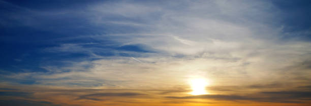 istock Sunset sky with clouds, blue, orange and yellow clouds and sun background 1720447460