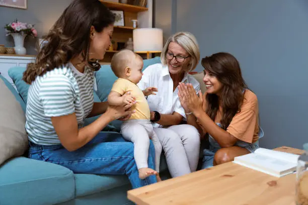 Photo of Grandmother, mother and baby in home for playing, quality time and bonding together in living room. Love, happy family aunt and mom of child with grandma play for loving, affection and happiness
