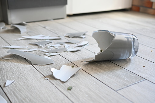 broken vase on the kitchen floor, gray broken vase, vase shards on the floor