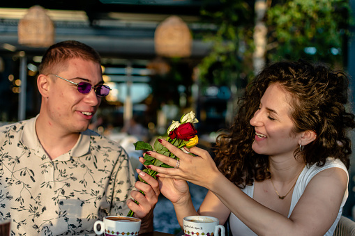 Symbolizing their blossoming love, the young man presents a thoughtful bouquet of flowers to his partner in the coffee garden, expressing his affection