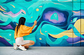 Street artist painting colorful graffiti on wall