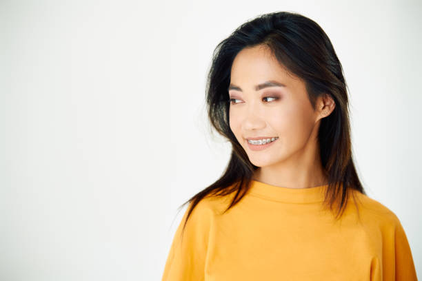 istock Young smiling asian woman with braces looking aside to copy space 1720510630