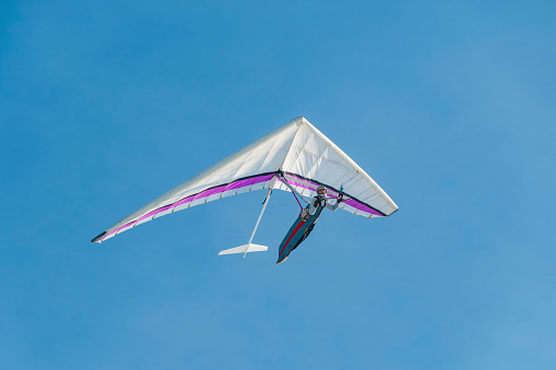 Hang glider pilot soaring in the blue sky. Extreme airborne sport
