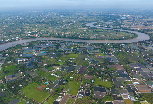 Aerial video of Vam Co river winding around dragon fruit gardens and shrimp ponds, Long An province, Vietnam