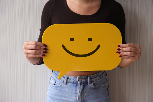 Woman holding yellow speech bubble with smiley face