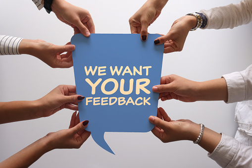 Women holding speech bubble with we want your feedback text