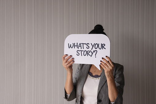 Woman holding speech bubble with What's Your Story? text.