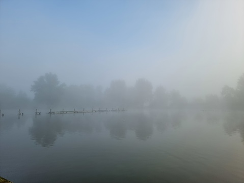 Landscape with a jetty at the lake. Nature with fog in the morning.