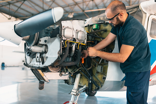 an aircraft mechanic is servicing the plane in the workshop