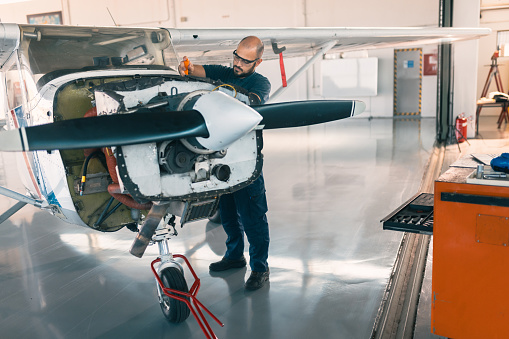 an aircraft mechanic is servicing the plane in the workshop