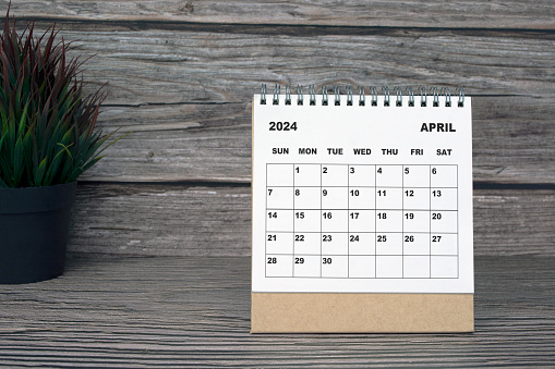 White April 2024 calendar on wooden desk with potted plant. 2024 New Year Concept