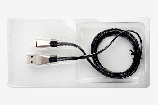 Black USB cable in plastic packaging on a white background. Copy space.