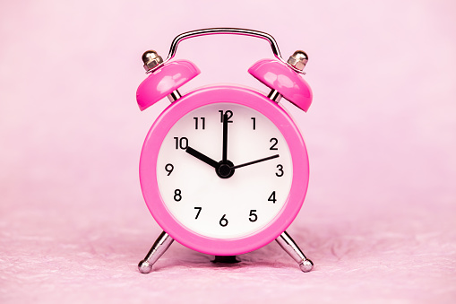Pink retro alarm clock. Daylight savings time or happy morning background with copy space