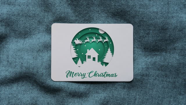 Green coloured paper cut style Santa Claus and flying reindeers animation with Merry Christmas text on Christmas card