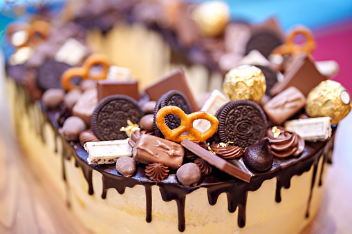 Chocolate cake with chocolate glaze, decorated with sweet chocolate candies, selective focus image.